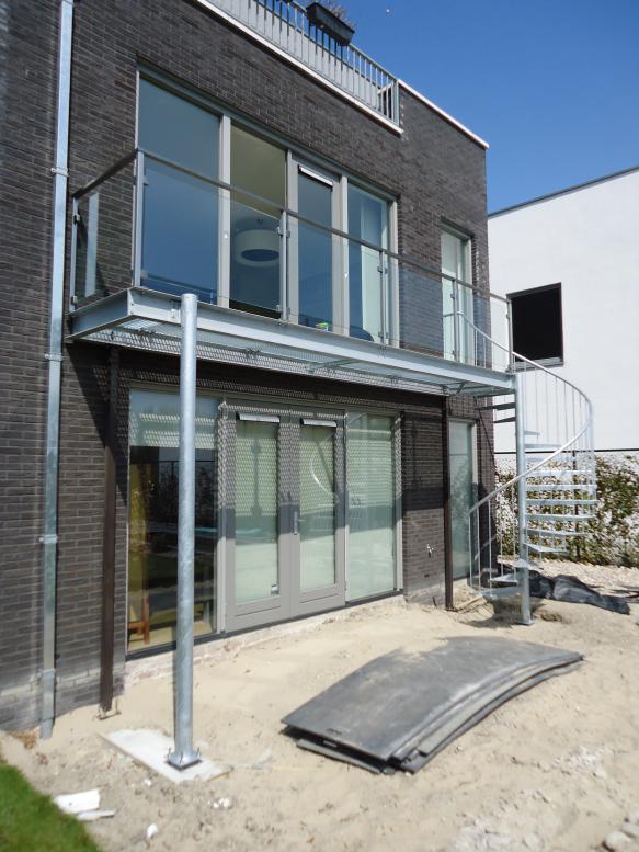 Balkon, rooster en spiltrap uit gegalvaniseerd staal, hekwerk van RVS met glazen panelen.